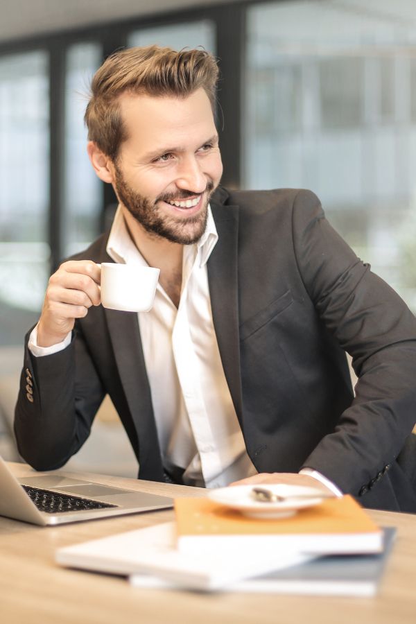Elegancki i uśmiechnęty biznesmen pije kawę